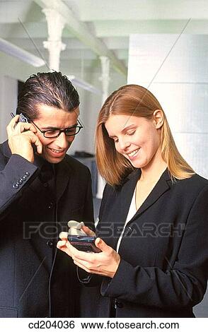 Businesswoman with personal organizer, businessman talking on cell phone View Large Photo Image Stock Photograph - Businesswoman with personal organizer, businessman talking on cell phone. Fotosearch