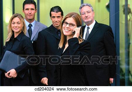 Executives looking at camera, businesswoman talking on cell phone View Large Photo Image Picture - Executives looking at camera, businesswoman talking on cell phone. Fotosearch