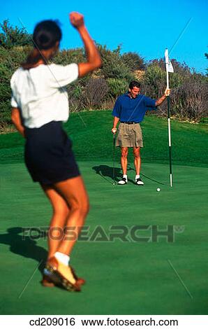Stock Photograph - Golfer sinking her put. Fotosearch