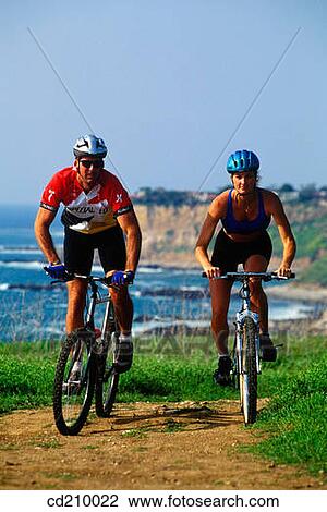 Man and woman mountain biking near the coast View Large Photo Image Stock Image - Man and woman mountain biking near the coast. Fotosearch