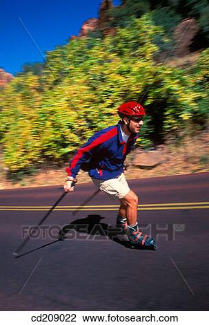 Stock Image - Man goes in-line skating on a mountain road. Fotosearch