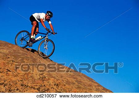 Man mountain biking down a slickrock hill View Large Photo Image Stock Photo - Man mountain biking down a slickrock hill. Fotosearch