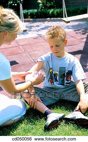 Mother putting a bandage on her son's arm View Large Photo Image Stock Photograph - Mother putting a bandage on her son's arm. Fotosearch