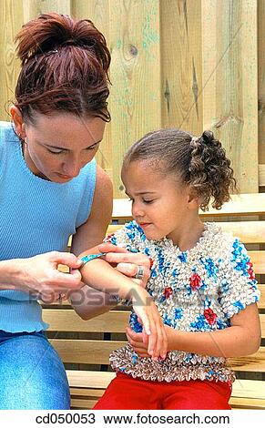 Mother putting adhesive bandage on her daughter's arm View Large Photo Image Stock Image - Mother putting adhesive bandage on her daughter's arm. Fotosearch