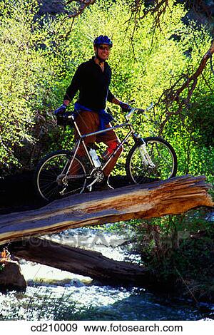Mountain biker standing over a river View Large Photo Image Stock Photo - Mountain biker standing over a river. Fotosearch