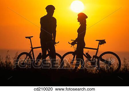 Silhouette of a man and woman mountain biking near the coast at sunset View Large Photo Image Stock Image - Silhouette of a man and woman mountain biking near the coast at sunset. Fotosearch