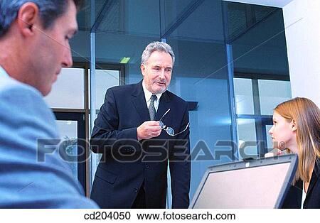Three executives in conference, businessman looking at laptop View Large Photo Image Stock Image - Three executives in conference, businessman looking at laptop. Fotosearch