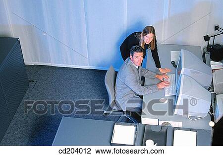 Two businesspeople in front of computer, businessman typing, both looking at camera View Large Photo Image Stock Image - Two businesspeople in front of computer, businessman typing, both looking at camera. Fotosearch