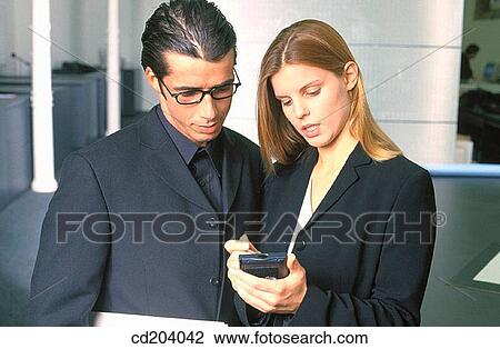 Stock Image - Two businesspeople looking at personal organizer. Fotosearch