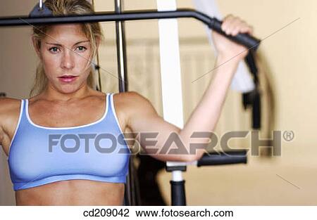 Woman working out by weight lifting on a home gym View Large Photo Image Stock Image - Woman working out by weight lifting on a home gym. Fotosearch
