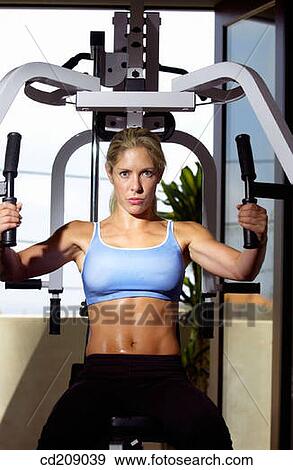 Woman working out by weight lifting on a home gym View Large Photo Image Stock Photo - Woman working out by weight lifting on a home gym. Fotosearch