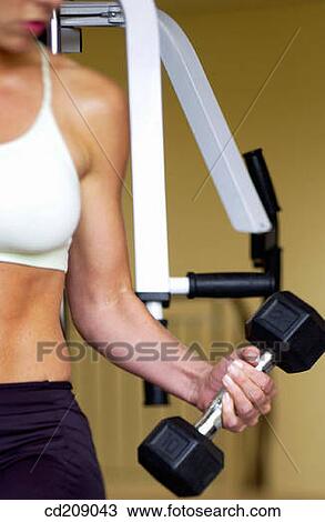 Stock Image - Woman working out by weight lifting. Fotosearch