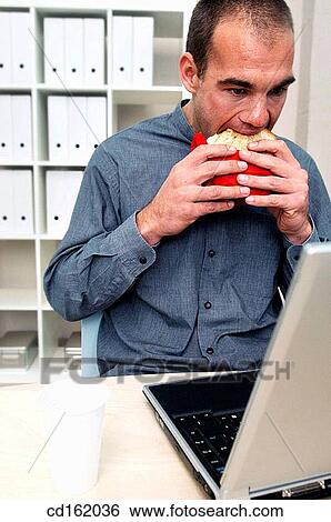 Stock Photograph - Businessman eating while working. Fotosearch