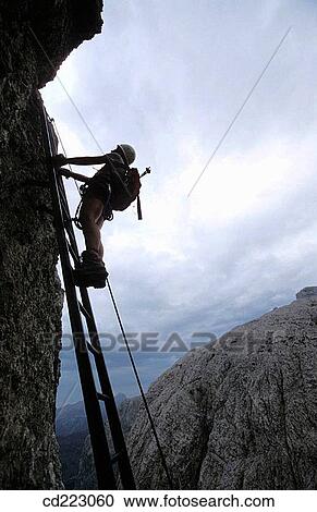 Outline of a climber on an iron ladder with cloudy sky in the background, Piscadue climbing trail, Dolomites, Sella, Italy View Large Photo Image Stock Image - Outline of a climber on an iron ladder with cloudy sky in the background, Piscadue climbing trail, Dolomites, Sella, Italy. Fotosearch