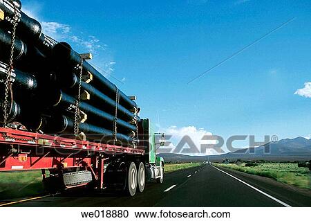 Stock Image - Semi-truck transporting freight down a deserted highway in the western United States.. Fotosearch