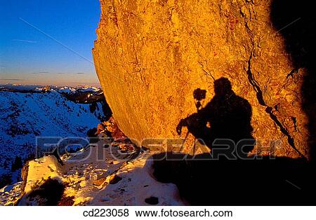 Stock Photo - Shadow of a photographer short time after sunrise at the snowy mount Plankenstein, Risserkogel, Upper Bavaria, Alps, Germany. Fotosearch