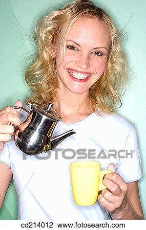 Stock Image - Woman pouring tea in cup. Fotosearch