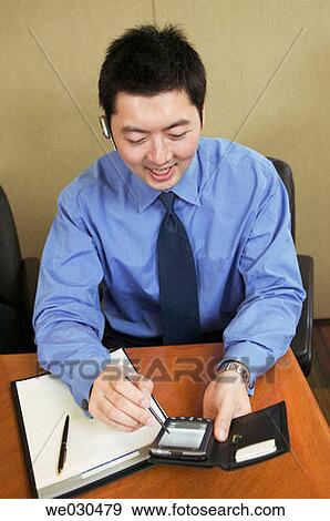 Asian male with cell phone remote ear/microphone bluetooth piece View Large Photo Image Stock Photo - Asian male with cell phone remote ear/microphone bluetooth piece. Fotosearch