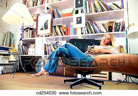 Stock Image - at-home, break, bookcase, blond, armchair. Fotosearch