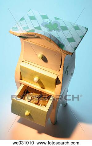 Stock Image - Coins in miniature chest of drawers. Fotosearch