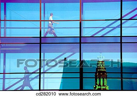 People crossing glass bridge in Nordea Bank building. Spire of Nikolaj Kirke in background, Copenhagen, Denmark View Large Photo Image Stock Image - People crossing glass bridge in Nordea Bank building. Spire of Nikolaj Kirke in background, Copenhagen, Denmark. Fotosearch