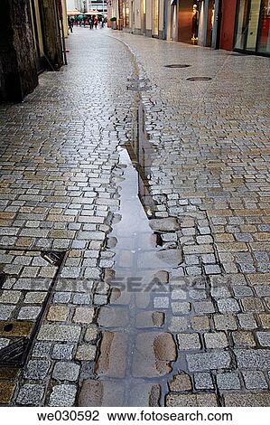 Stock Image - Puddle on cobble-stone pavement after heavy shower, Ratisbone / Regensburg, Upper Palatinate, Bavaria, Germany. Fotosearch