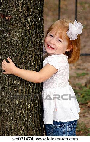 Toddler girl hugging a tree View Large Photo Image Picture - Toddler girl hugging a tree. Fotosearch