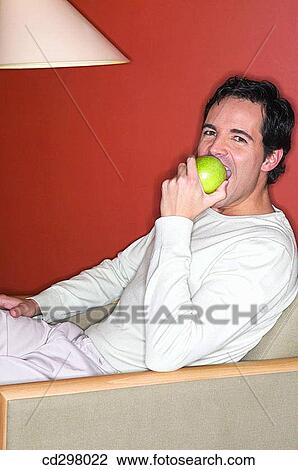 Stock Image - apple, bite, at-home, armchair, 30's. Fotosearch