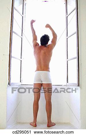 Stock Image - at-home, bedroom, barefoot, back view, Arms raised. Fotosearch