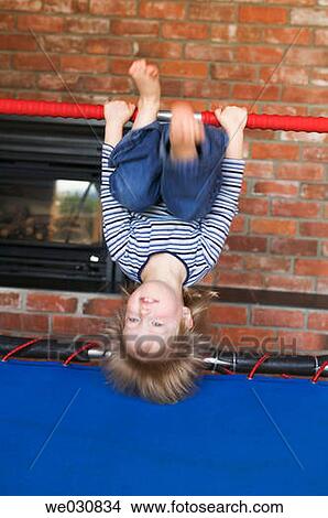 Picture - Caucasian girl 3 years old. Upside down on trampoline bar. Fotosearch