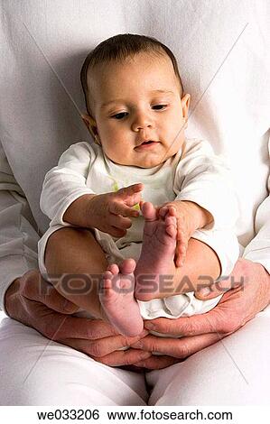 Stock Photograph - Little baby playing with his feet.. Fotosearch