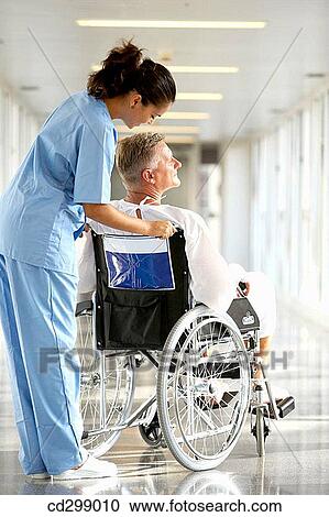 Stock Image - Nurse pushing patient in wheelchair. Fotosearch