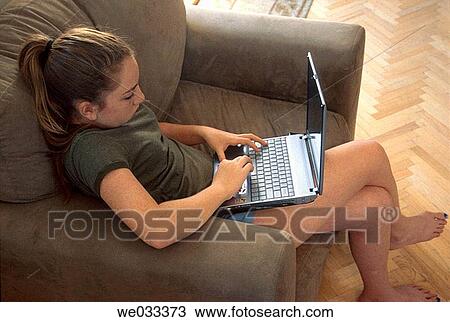 Teen girl using laptop while relaxing in a stuffed chair View Large Photo Image Stock Image - Teen girl using laptop while relaxing in a stuffed chair. Fotosearch