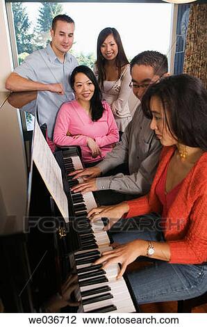 Stock Image - Asian Friends Sitting Around a Piano. Fotosearch