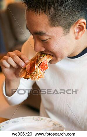Asian man eating pizza View Large Photo Image Stock Image - Asian man eating pizza. Fotosearch