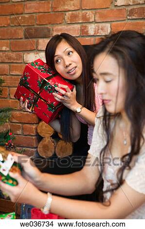 Asian woman guessing what's in her Christmas gift View Large Photo Image Picture - Asian woman guessing what's in her Christmas gift. Fotosearch