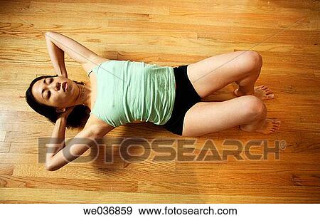 Stock Photo - Asian woman on laying on wood floor doing exercise. Fotosearch