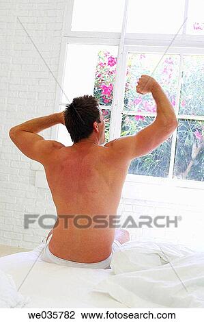 Stock Image - at-home, bedroom, bed, back view, Arms raised. Fotosearch