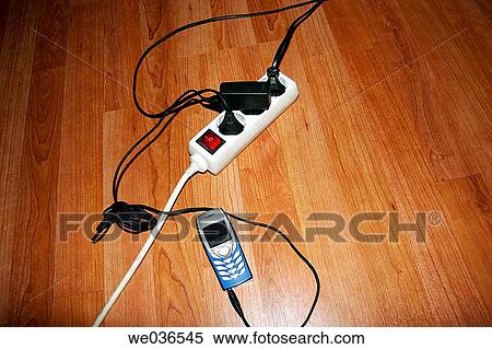 Stock Photography - Cell phone by multiple socket. Fotosearch