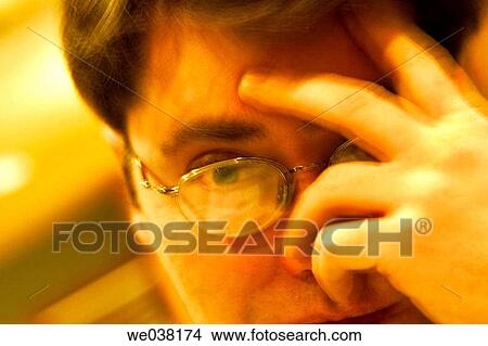 Close-up of a young man, wearing glasses, with his hand resting on his head View Large Photo Image Picture - Close-up of a young man, wearing glasses, with his hand resting on his head. Fotosearch