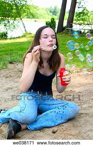 Teenage girl, sitting on the ground, blowing soap bubbles View Large Photo Image Stock Image - Teenage girl, sitting on the ground, blowing soap bubbles. Fotosearch