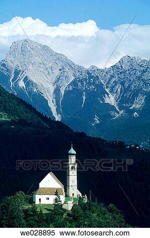 Stock Photography - The San Daniele area: fresh aromatic air of the Alps combine with the soft damp currents originating from the Adriatic sea: ideal conditions necessary for seasoning. Church Pieve di San Pietro in the Carnia mountains. Italy.. Fotosearch