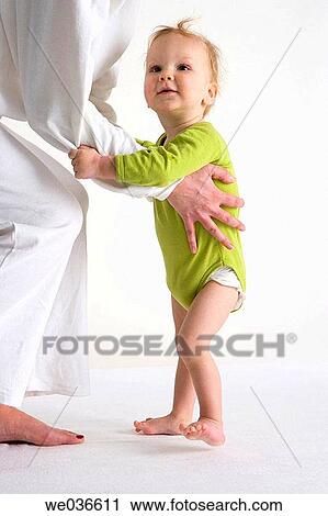 Stock Image - Toddler standing near his mothers legs. Fotosearch