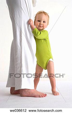 Toddler standing near his mothers legs View Large Photo Image Stock Image - Toddler standing near his mothers legs. Fotosearch