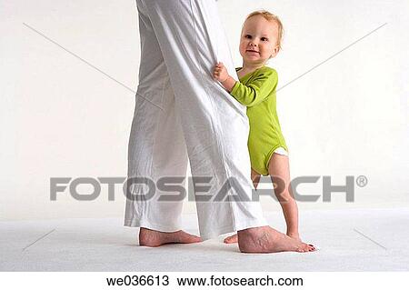 Toddler standing near his mothers legs View Large Photo Image Stock Image - Toddler standing near his mothers legs. Fotosearch