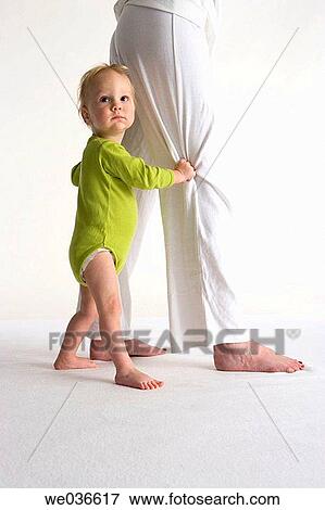 Stock Photo - Toddler standing near his mothers legs. Fotosearch
