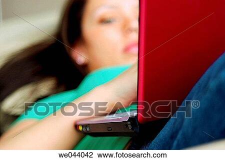 Stock Image - 20 years old girl working on laptop computer in livingroom of home on sofa.. Fotosearch