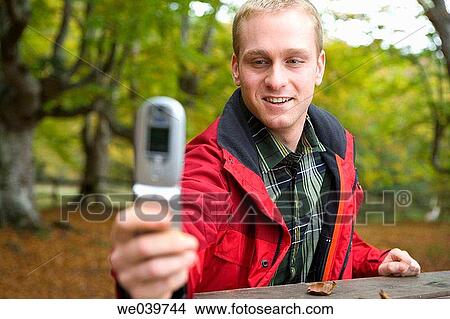 Picture - blond, cell phone, camera, autumn. Fotosearch