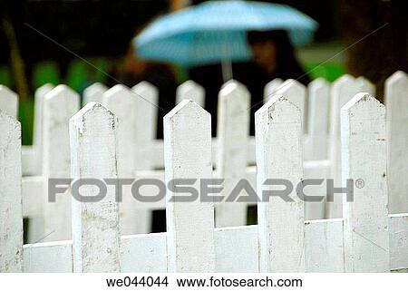 Girl walking behind white picket fence at park with blue umbrella Vancouver BC Canada. View Large Photo Image Picture - Girl walking behind white picket fence at park with blue umbrella Vancouver BC Canada.. Fotosearch