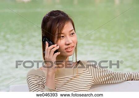 タイ バンコク Lumpini 公園 タイ人 女の子 Jane ベンチの着席 そして 呼出し 上に 移動式 電話 Mr 0604 0004 Jan ストックイメージ We Fotosearch